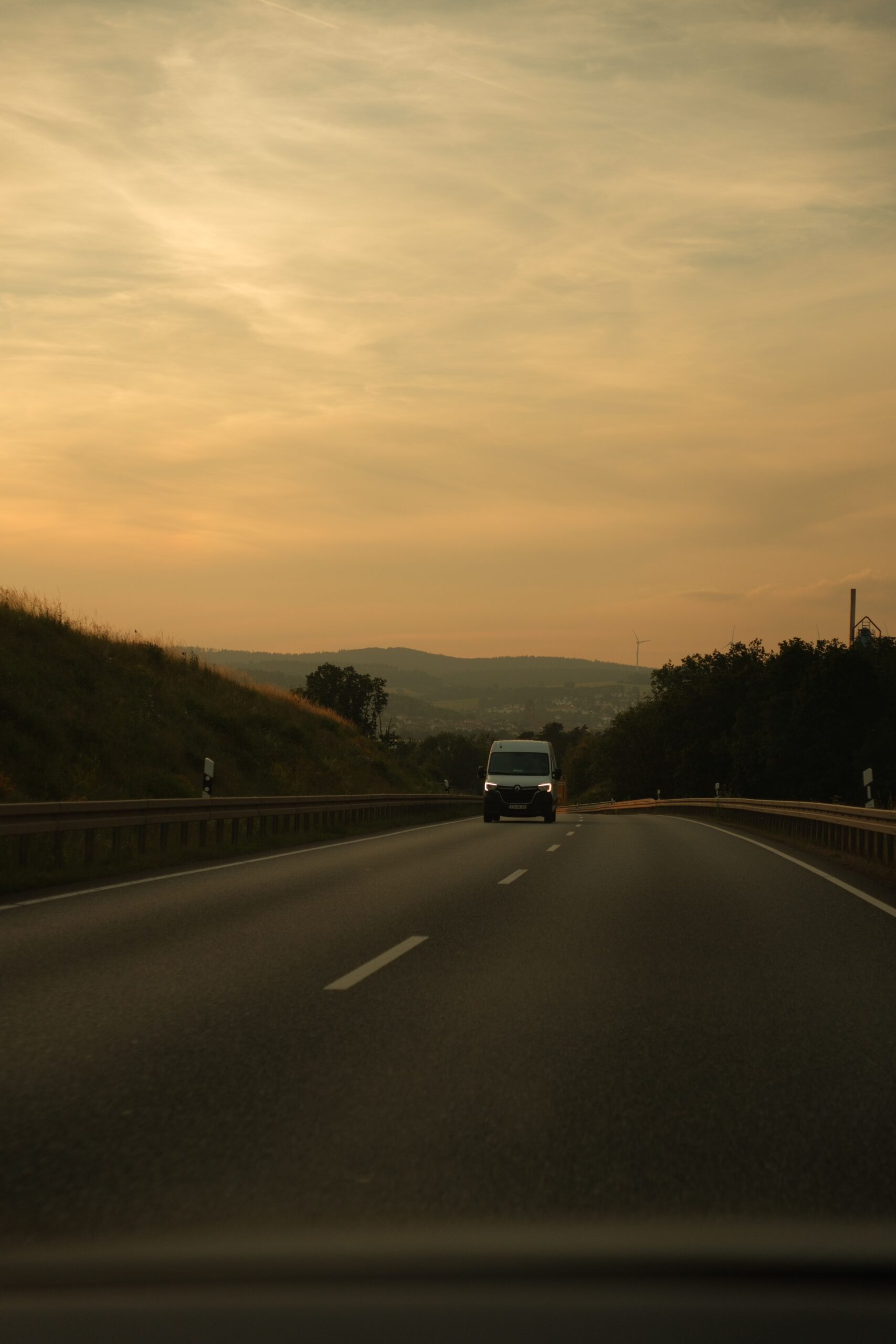 A tranquil highway drive amidst hills during a golden sunset, capturing nature's serene beauty.